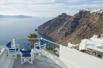 Fototapeta na wymiar Whitewashed Houses on Cliffs with Sea View, Table and Chairs in Fira, Santorini, Cyclades, Greece