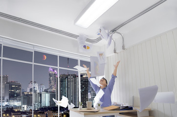 Successful business man tossing papers celebrating at the office and happy while celebrating...