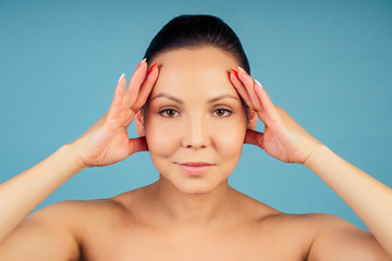 portrait of a beautiful and young woman with fresh and clean skin on a blue background in the studio