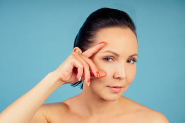 Naklejka premium portrait of a beautiful and young woman with fresh and clean skin on a blue background in the studio