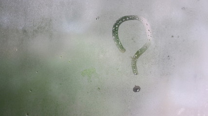 sign question mark on window with raindrops