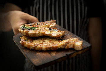 Image cooking on kitchen. Master Chef holding steak. Woman Chef kitchen holding grilled beef steak on plate with organic vegetable decoration. beef or pock. Selective focus.
