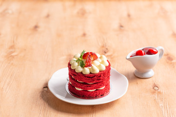 Red velvet cake, fresh strawberry, cherry jam with white plate on wooden table.