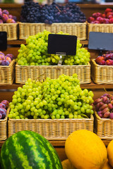 Fresh grapes bunch lies in a wicker basket in the counter of a small market. 