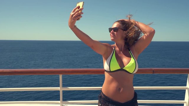 Bikini woman on a cruise ship taking selfie on phone