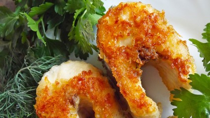Tasty fried pike with greens on a white plate.