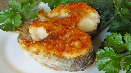Tasty fried pike with greens on a white plate.