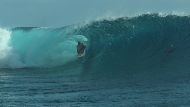 SLOW MOTION, CLOSE UP: Fearless young surfboarder rides inside a spectacular barrel wave. Breathtaking shot of emerald wave curling and splashing over a surfer having fun in sunny French Polynesia.