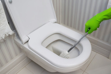 Toilet bowl cleaning. cleaner in green rubber gloves