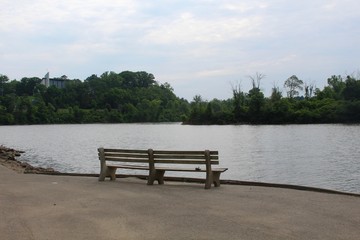 Fototapeta na wymiar The wood empty park bench near the lake in the park.