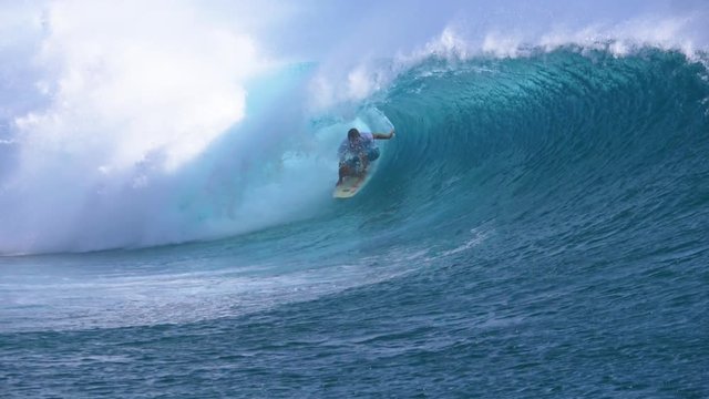 SLOW MOTION, CLOSE UP: Young professional surfboarder finishes riding another epic tube wave on a sunny day in French Polynesia. Surfer having fun in the emerald water on a perfect day for surfing.