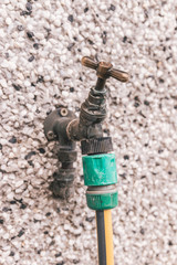Close up of a hose pipe connected to a water valve on the wall