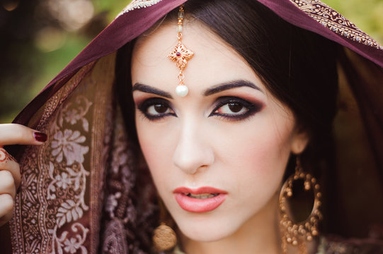 Portrait of beautiful indian girl . Young hindu woman model with tatoo mehndi and kundan jewelry.