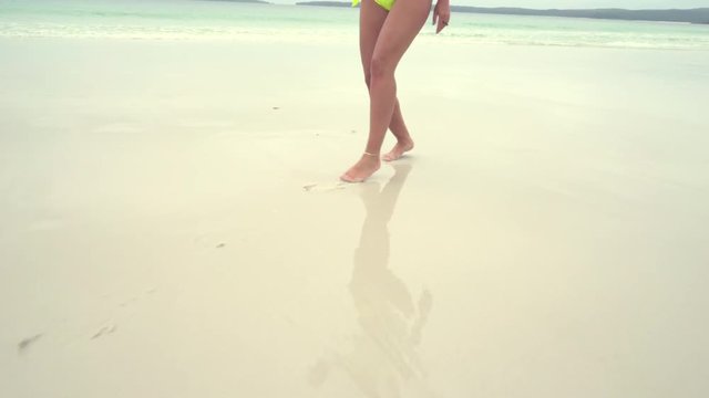 Barefoot woman walking on sandy beach. Steadicam shot