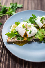 Homemade poached eggs on toast with fresh herbs and pepper