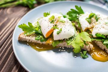 Homemade poached eggs on toast with fresh herbs and pepper