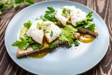 Homemade poached eggs on toast with fresh herbs and pepper