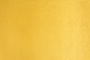 Obraz premium yellow texture of the surface of the wall covered with decorative plaster of the woodworm type, close-up architecture abstract background