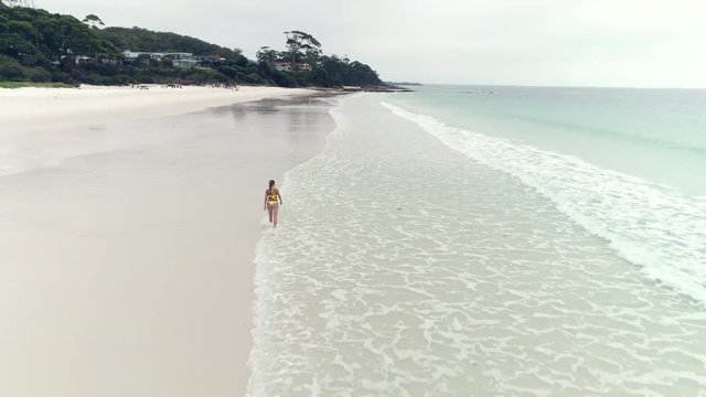 Aerial view of bikini woman walking along in sandy beach