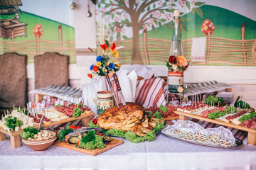 Meat assortment of sausage, smoked meat, on a wooden board on wedding table