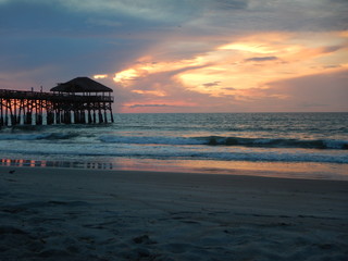 The view of the sun rising on Cocoa Beach in Florida with a view of the pier in the distance 