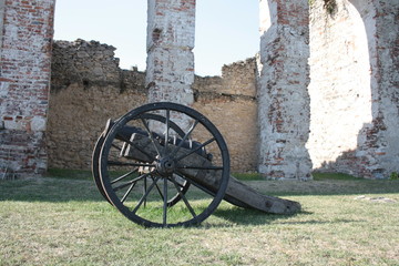 An old cannon on the background of castle ruins