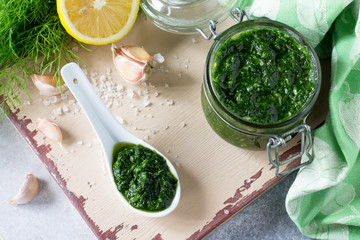 Preserving sauce dill with garlic and olive oil on the kitchen wooden background. Top view flat lay background, copy space.