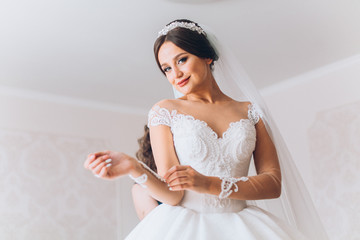 Bride preparation before wedding ceremony.  Pleasant young bridesmaids helping the bride to get...