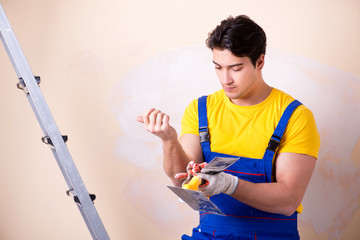 Young contractor employee applying plaster on wall