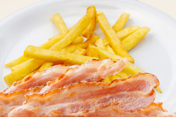 Bacon and French fries on a white plate. Brunch. Breakfast. Snacks. Food. Picnic. Barbecue.