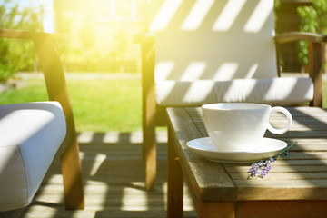 Cup of tea served on natural wood table in the provence style backyard garden terrace