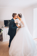 First meeting of bride and groom in hotel room. Newlyweds couple smiling at wedding day. Happy marriage concept