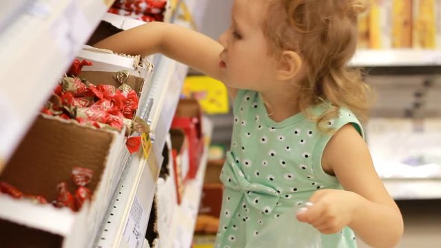 Child in the supermarket buys candies and sweets. Shopping store warehouse