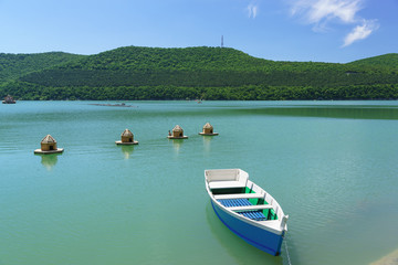 Fototapeta na wymiar Bright blue rowing boat on the emerald water of the mountain lake Abrau-Durso
