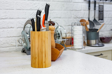 Kitchen knives in a special wooden stand with spice jars. Close-up. Kitchen concept