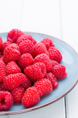 Fresh raspberries in a plate on a  vintage background.