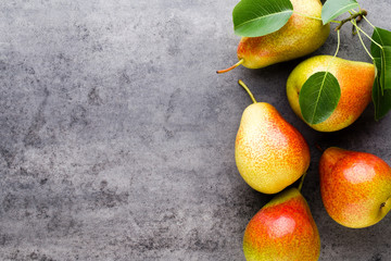 Fresh bio pear with leaves on the plate. Gray stone table.