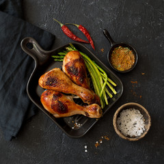 Grilled chicken drumsticks and asparagus on ceramic pan