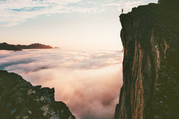 Traveler man standing on the edge cliff over clouds sunset mountains travel adventure lifestyle...