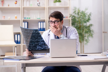 Young doctor looking at x-ray images in clinic