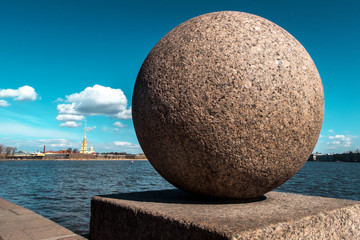 A granite ball is an element of the fencing of the Neva embankment on the background of the Peter and Paul Fortress. Stones St. Petersburg.