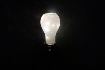 Glowing lightbulb on black background, idea concept