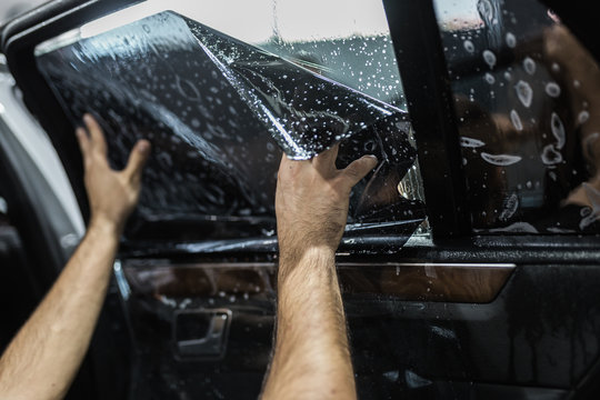 Fototapeta Car tinting - Worker applying tinting foil on car window.