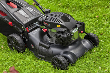 A four-stroke gasoline lawnmower on top of the grass in the garden
