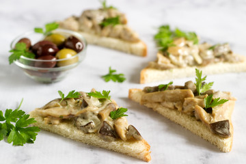 Triangular sandwiches with summer mushrooms cooked with cream and herbs served with olives.