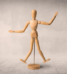 Wooden mannequin posed in front of a greyish background