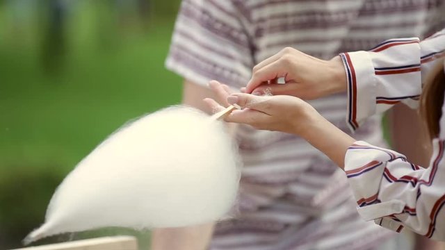 Video theme is a small business cooking sweets. Caucasian man Hands close-up of a street vendor making a candy floss of white color. In the summer in the park
