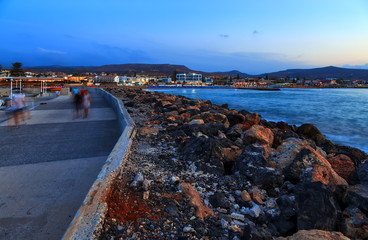 Beautiful sea with evening soft light of the sunset against cloudy sky with coastal line with stones and promenade path in Gouves, resort town, on Crete. Greece © vladimircaribb