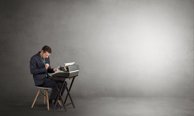 Man working hard on a typewriter in an empty space
