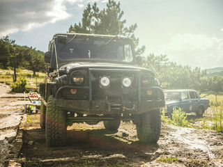 Fototapeta premium front view of massive 4x4 off-road car on the dirty ground panorama in mountains